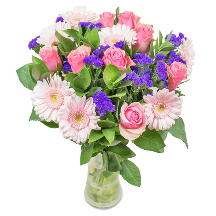 Set against a crisp, clean background, this eye-catching floral bouquet channels the fresh, vibrant spirit of Highams Park. At its centre are about eight pink roses-many in soft, dusky hues, some tightly held, others starting to bloom-displaying that classic, spiral beauty reminiscent of heritage gardens along The Avenue. Intertwined are five to seven pale pink gerbera daisies with wide, radiating petals and creamy centres, their sunny freshness echoing the friendly faces seen at local bakeries near Highams Park Station. Dotted throughout the bouquet, clusters of rich purple statice add a dramatic visual pop and textured contrast, much like the wildflowers found on the edges of Rolls Sports Ground. The deep green foliage cradling the arrangement brings a feeling of natural abundance and local parkland serenity, and the slender glass vase lets every stem and drop of water shine through. Crafted for birthdays, anniversaries, or the simple pleasure of a beautiful home display, this bouquet delivers a message of cheerful affection and style to all corners of Highams Park.